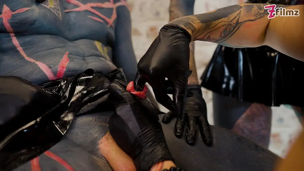 3 dominatrix streching the ureta of a tattooed sub and fingering his dick