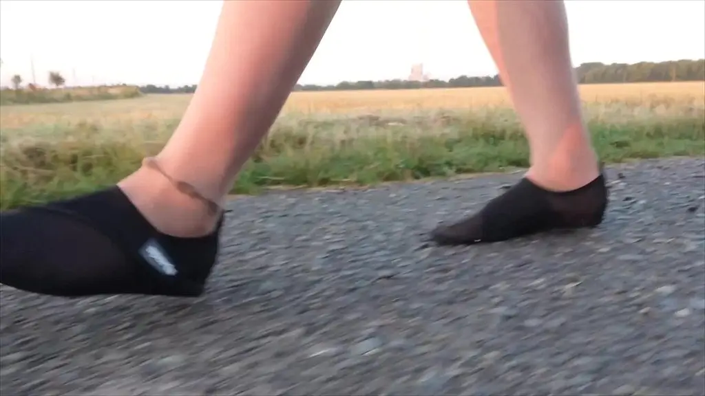 helle feinstrumpfhose und strandschuhe in der pfutze